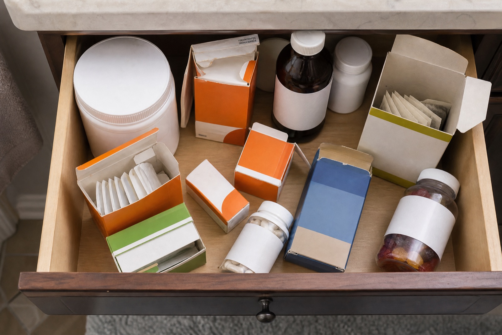 An open bathroom drawer crowded with half-used laxatives, fiber supplements, and teas